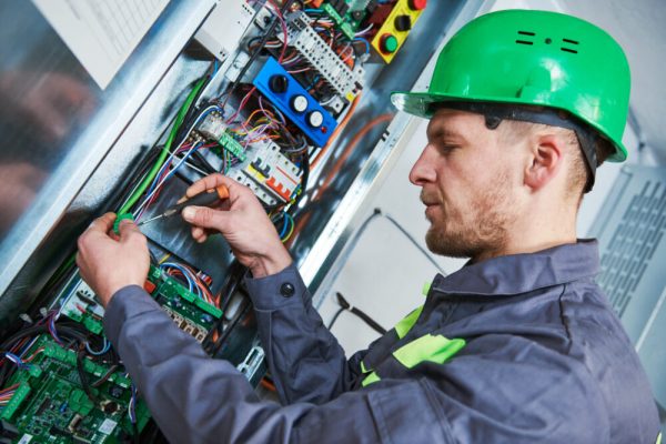 Elevator installation and maintenance. lift machinist electrician worker adjusting eelectronic control panel in engine room